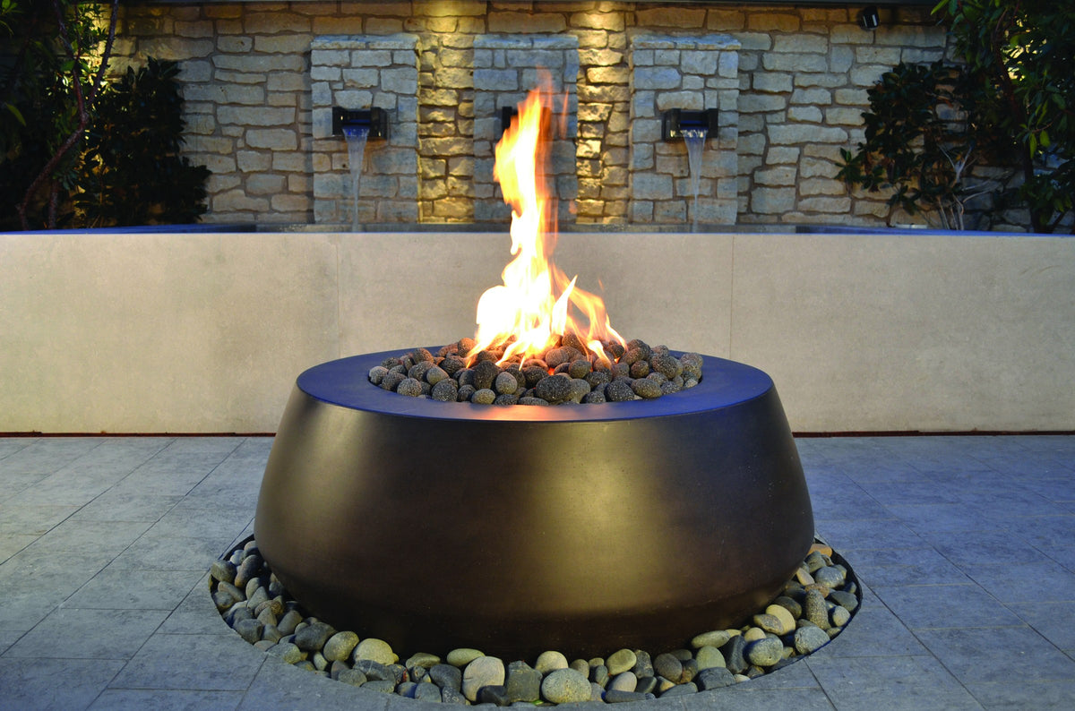 Belize round concrete gas fire bowl lit on a stone patio