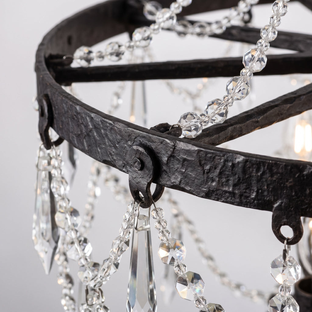 Close-up detail of crystal strands attached to dark iron wheel frame showing rustic-glam contrast