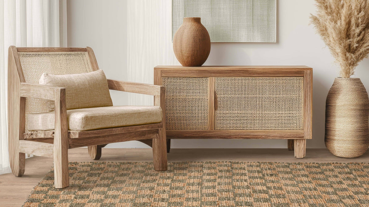 A cane armchair and sideboard with a ceramic vase, on a jute rug
