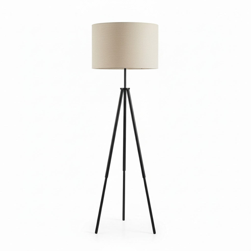 Black tripod floor lamp low angle view showing splayed legs and drum shade
