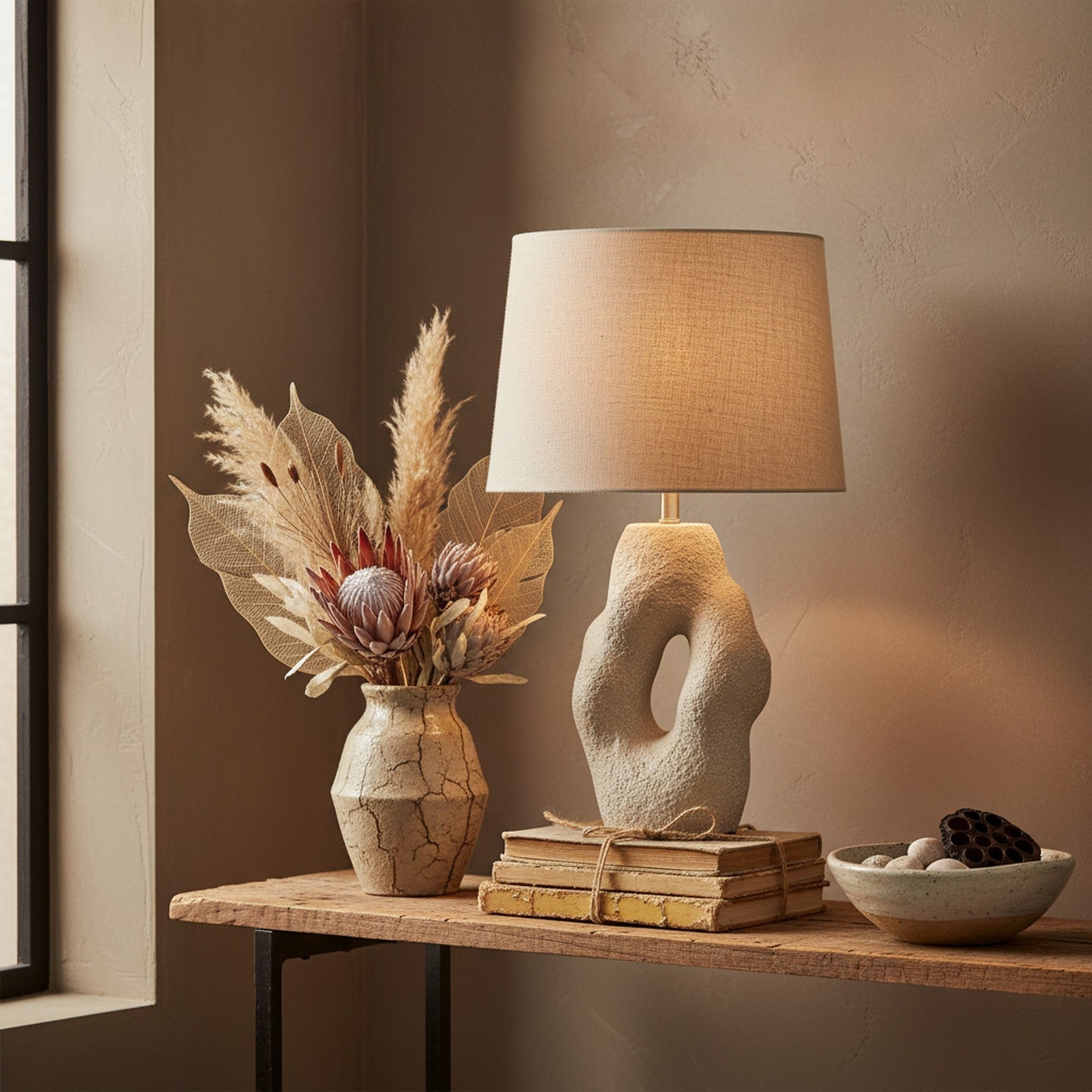 Cast stone sculptural lamp in wabi-sabi living room vignette with dried botanicals and books