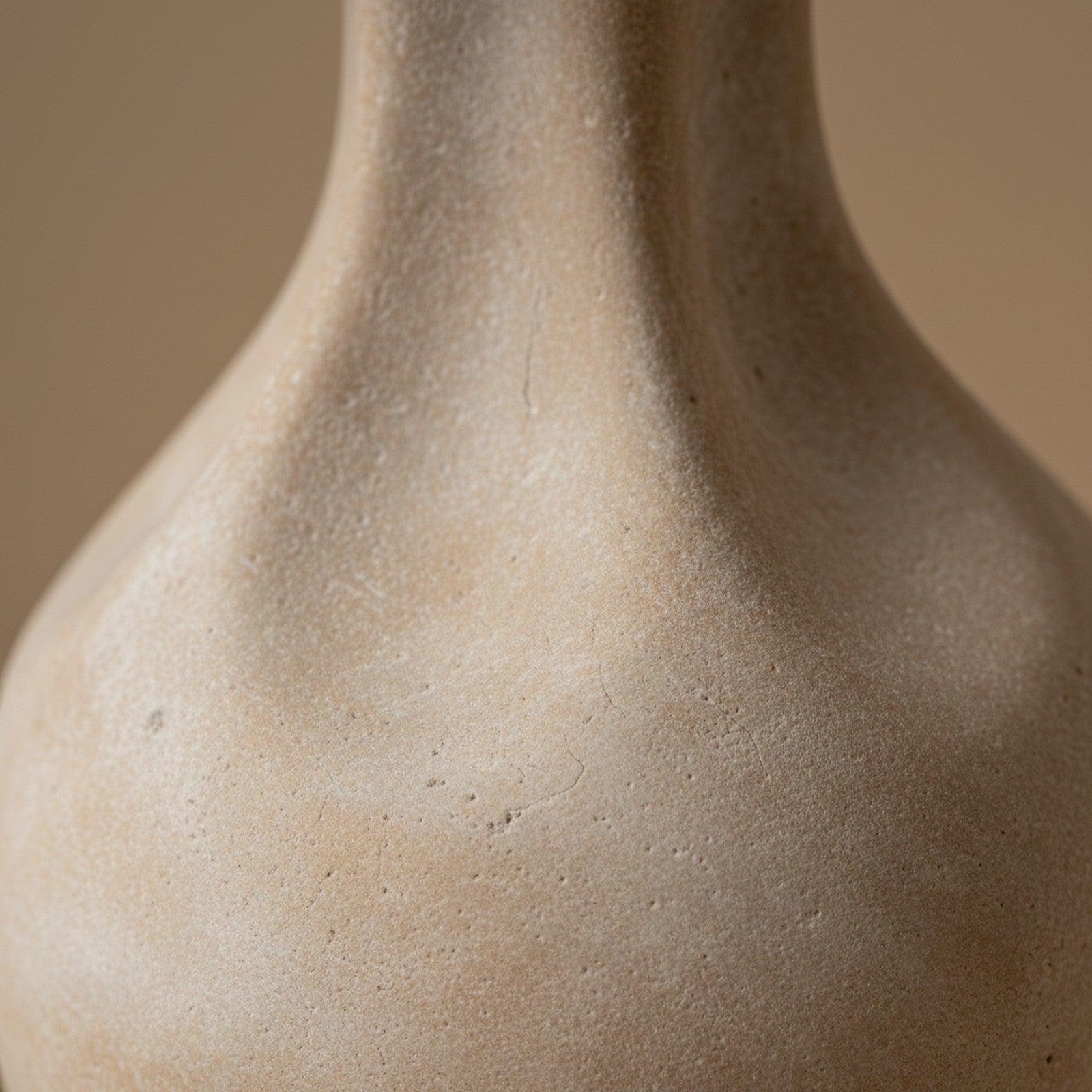 Close-up of cast stone lamp surface showing chalky matte finish and subtle beige color variations