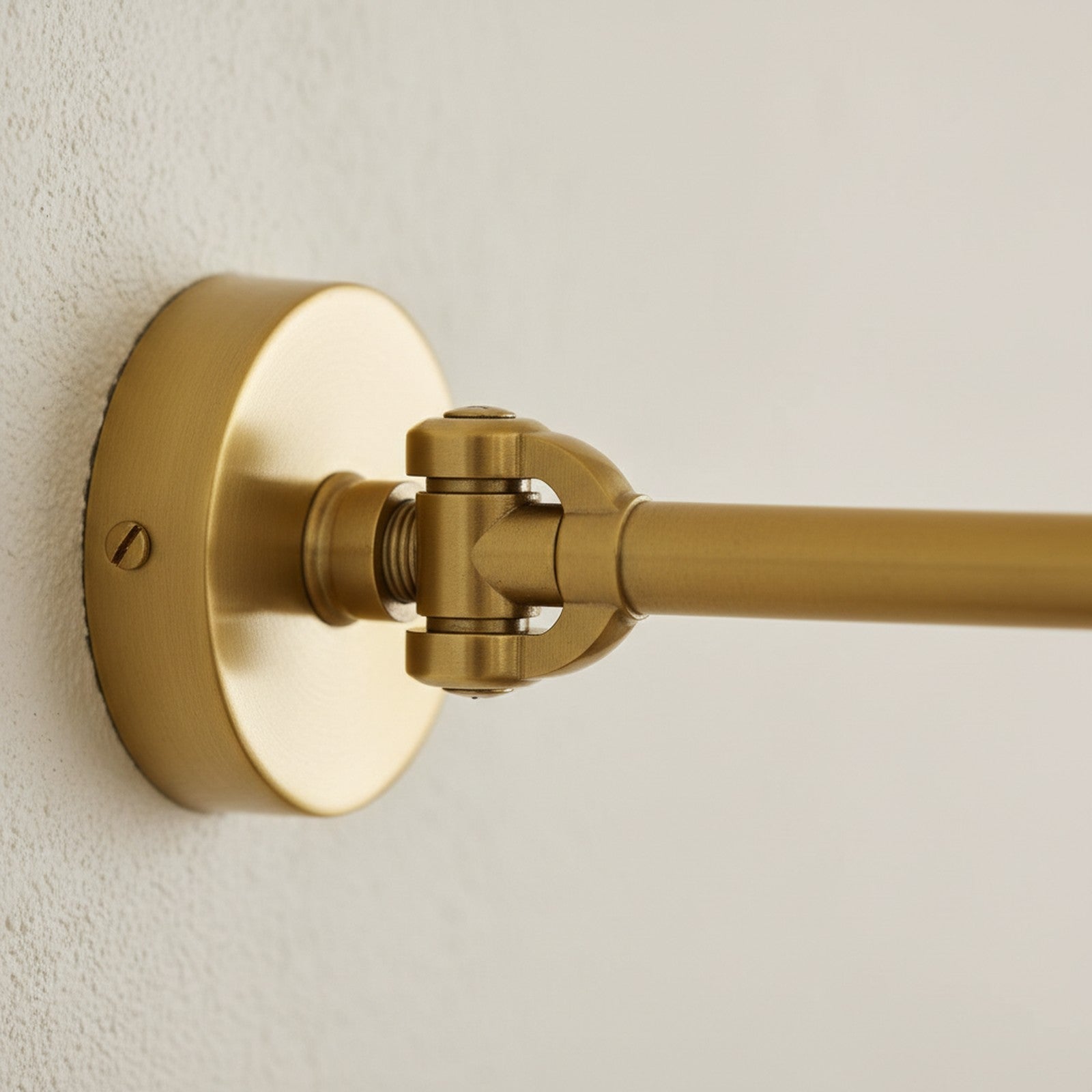 Close-up of brass swing-arm pivot joint showing precision joinery and warm brass finish